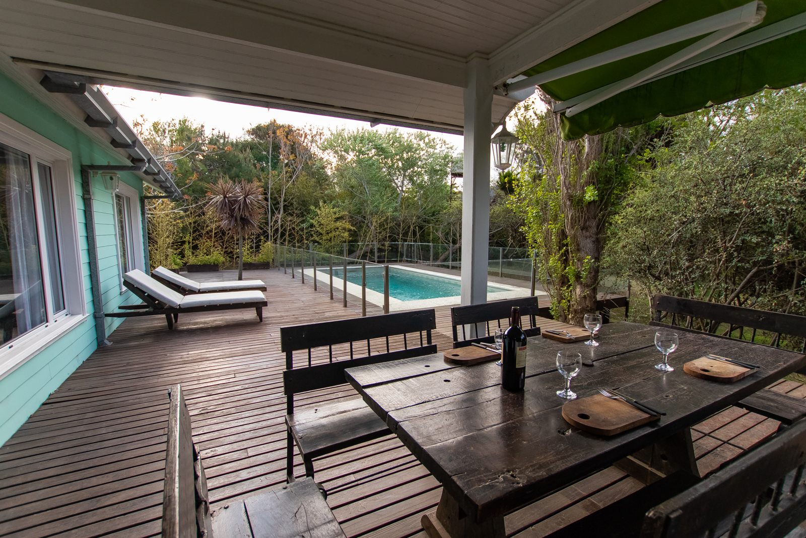 Galería techada de la Casa Verde con la mesa puesta y la piscina al atardecer